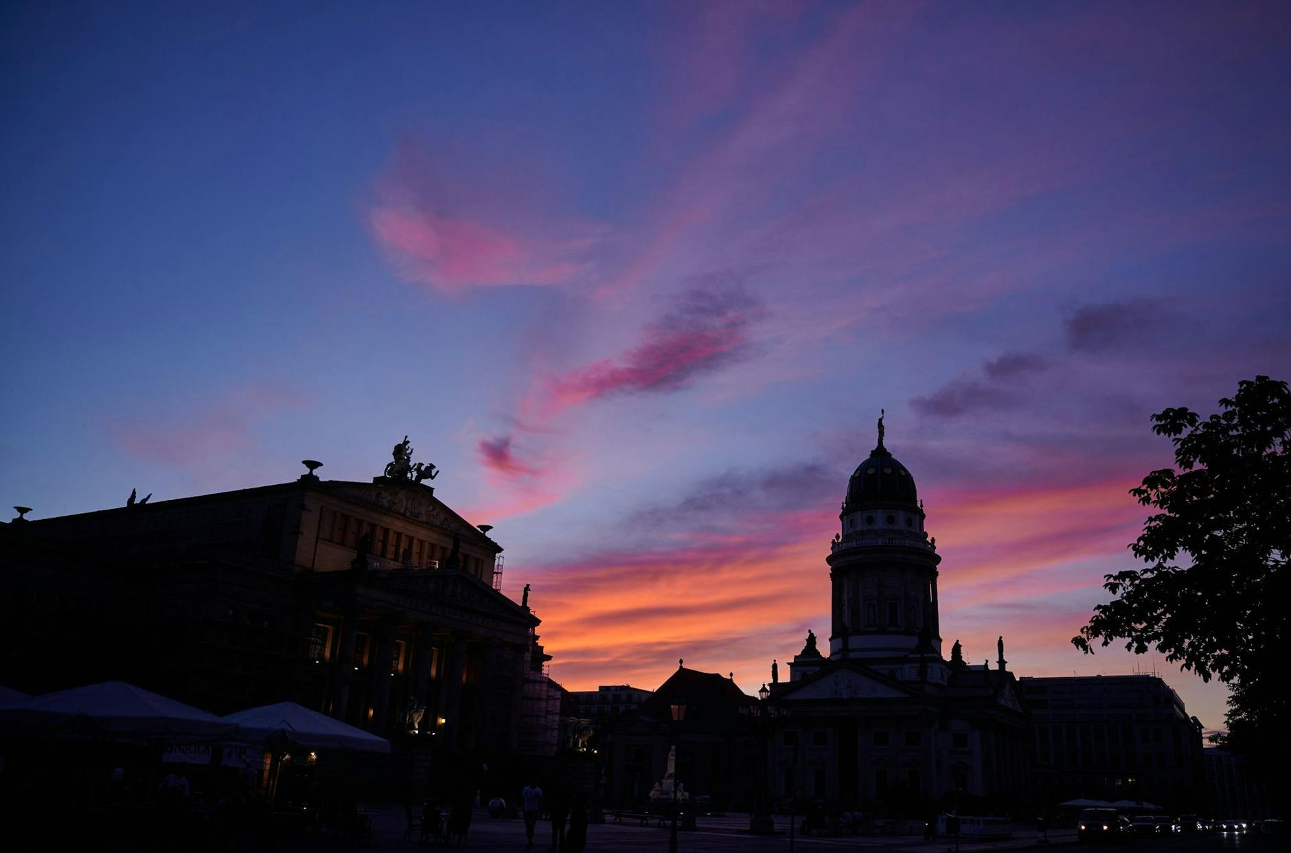 Nach einem warmen Sommertag taucht die untergegangene Sonne den Himmel über dem Gendarmenmarkt in Berlin in bunte Farben.