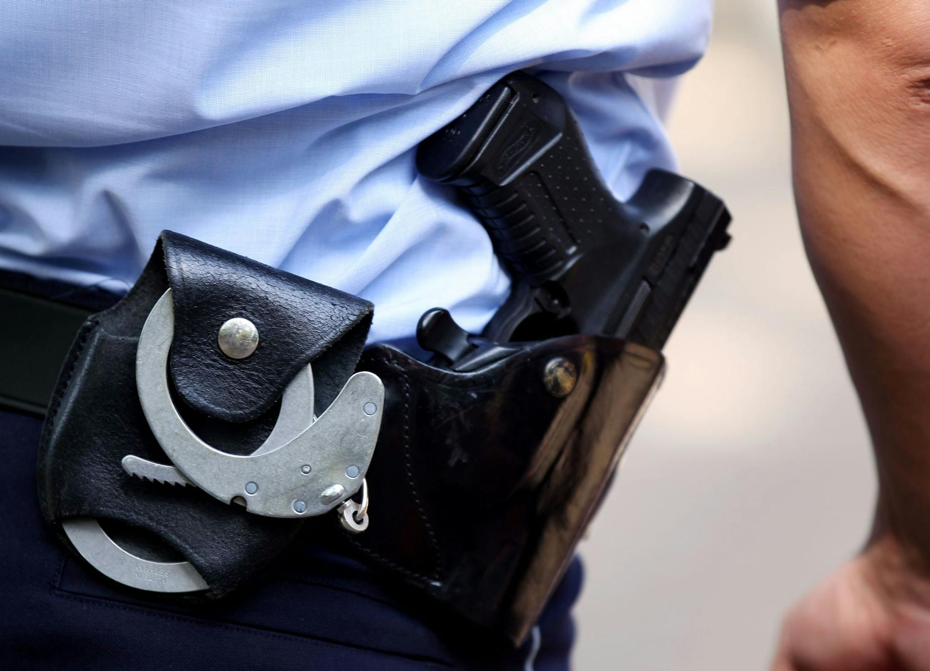 ARCHIV - Ein Polizist trägt Handschellen und seine Dienstwaffe bei sich.