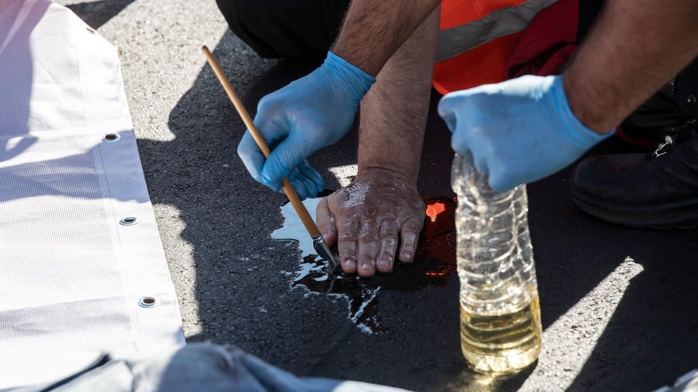 Berlin, Frankfurter Tor: Ein Polizist löst am Donnerstag die festgeklebte Hand eines Aktivisten von der Straße ab. Dafür benutzt er Sonnenblumenöl.