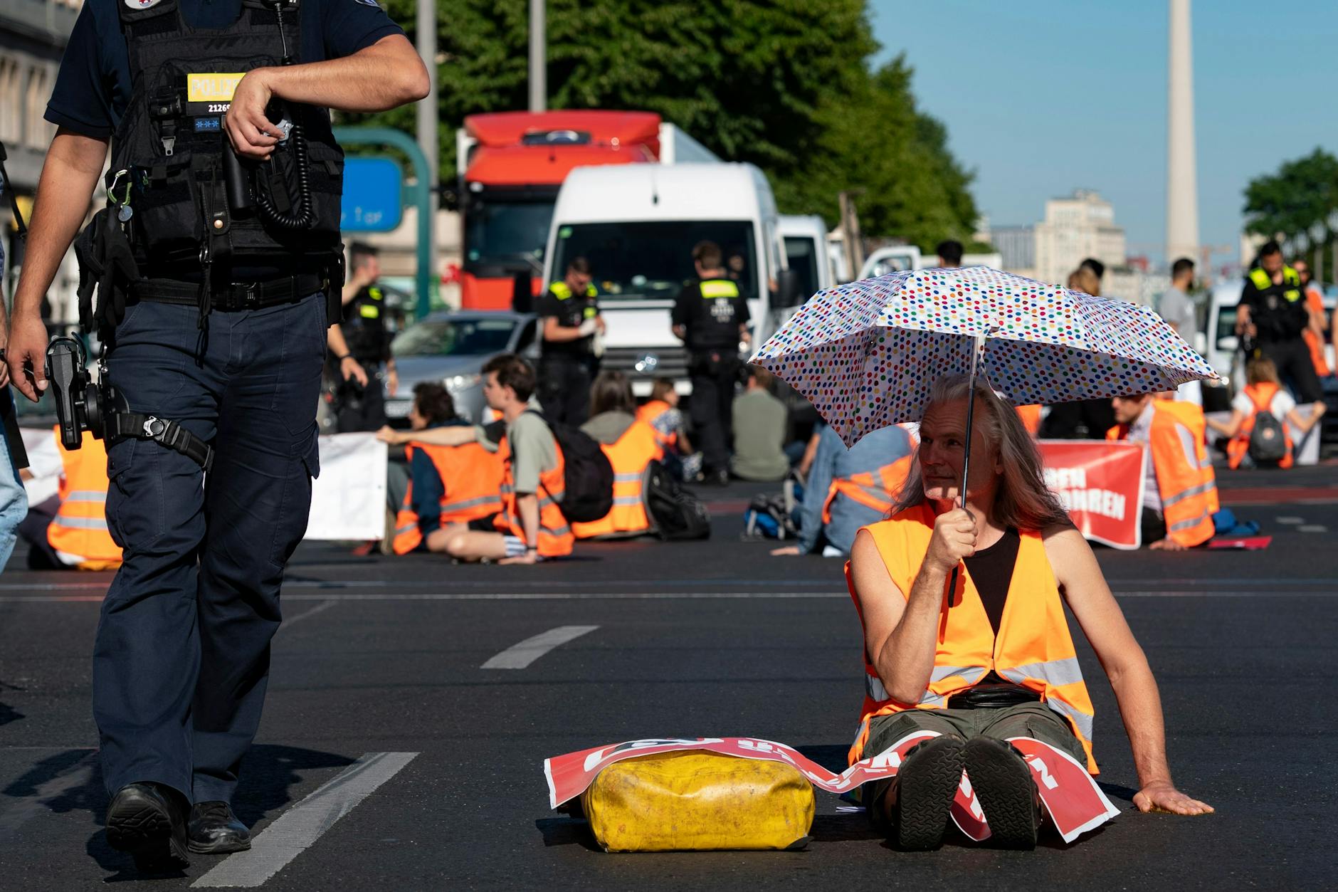 Aktivisten der Letzten Generation blockieren die Fahrbahn in der Karl-Marx-Allee.