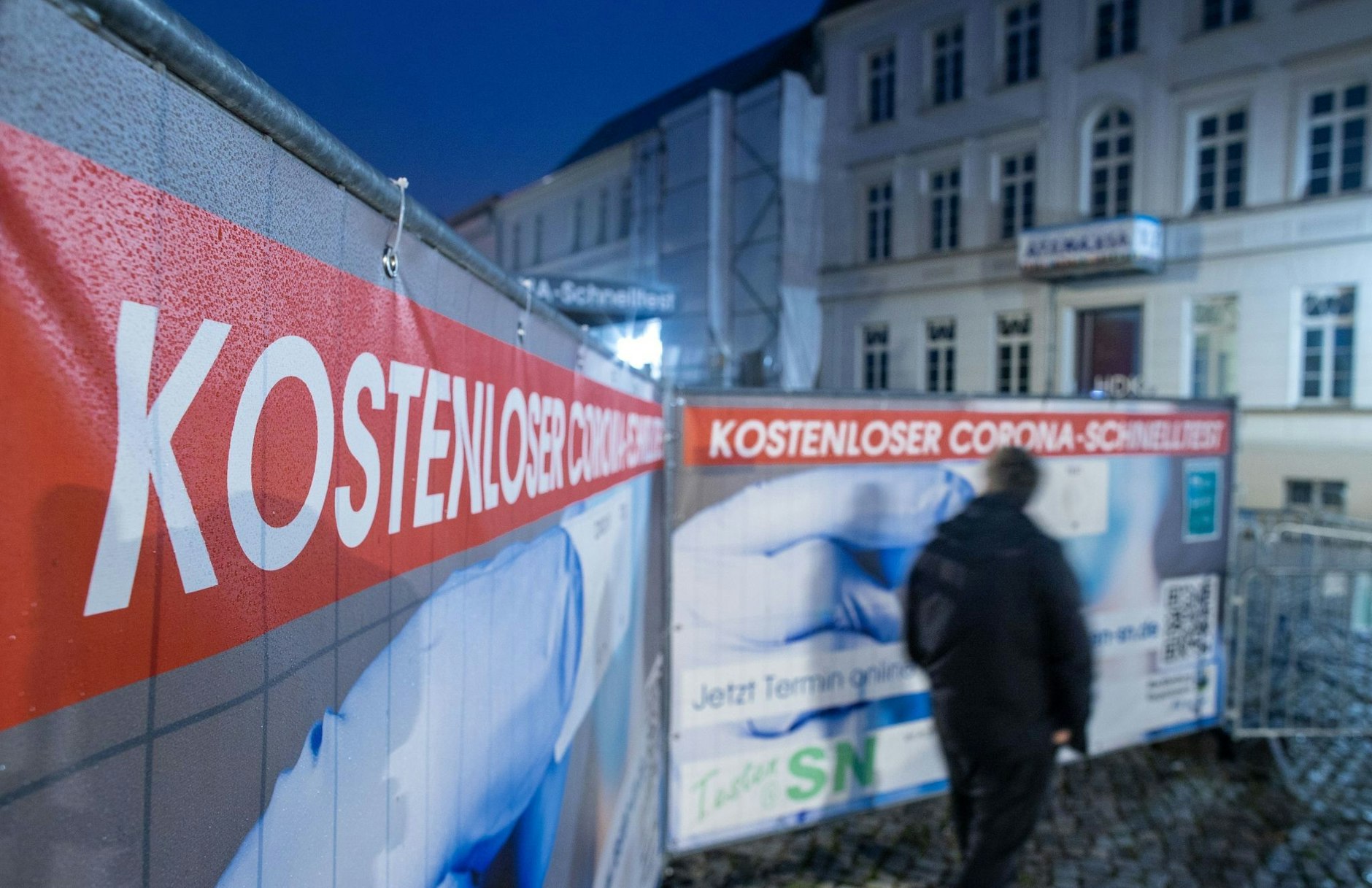 ARCHIV - Ein Passant geht an einem Corona-Testzentrum im Schweriner Stadtzentrum vorbei.  a