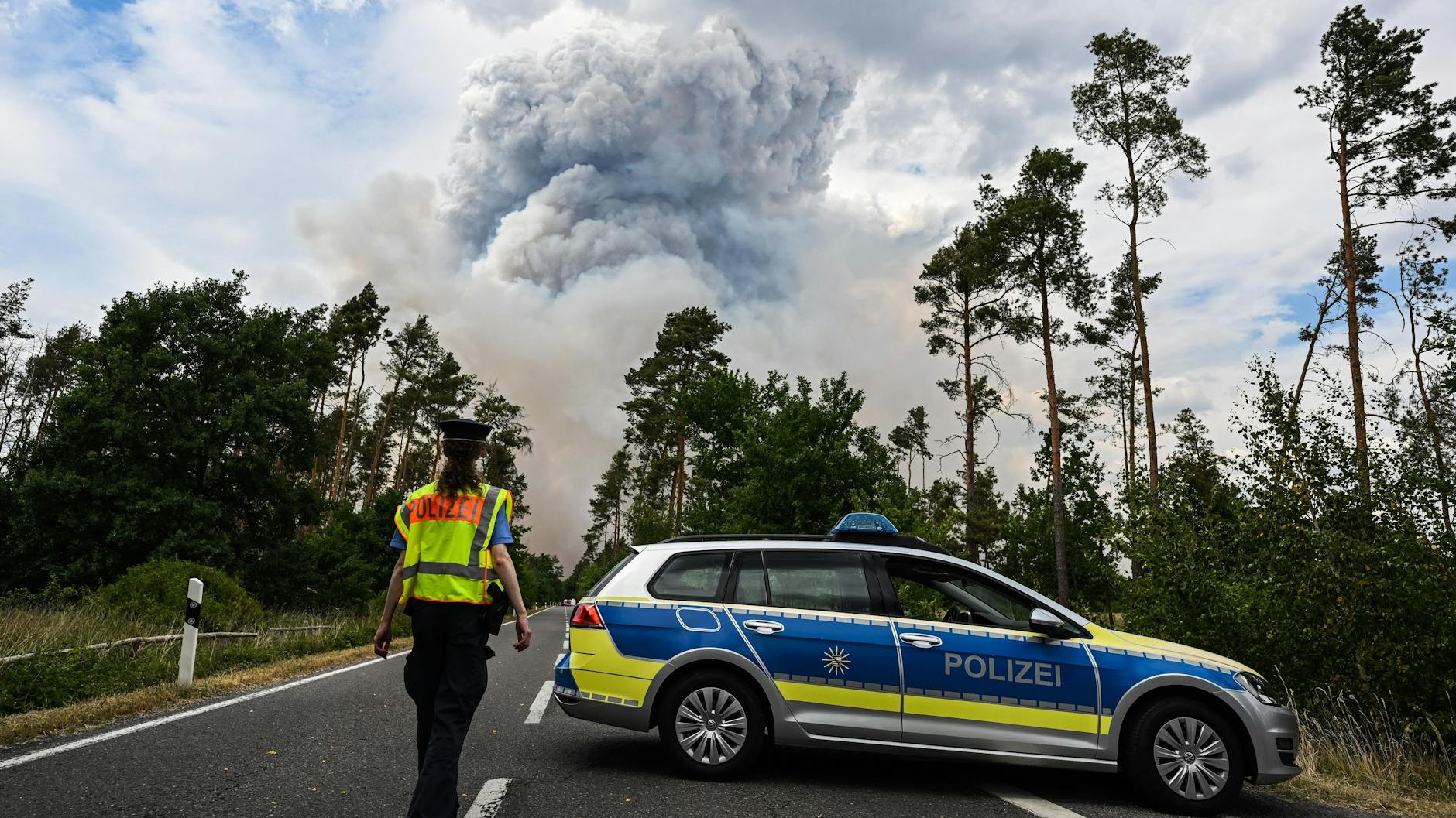 Ein Polizeiauto sperrt die Straße zum Waldbrand-Gebiet ab.