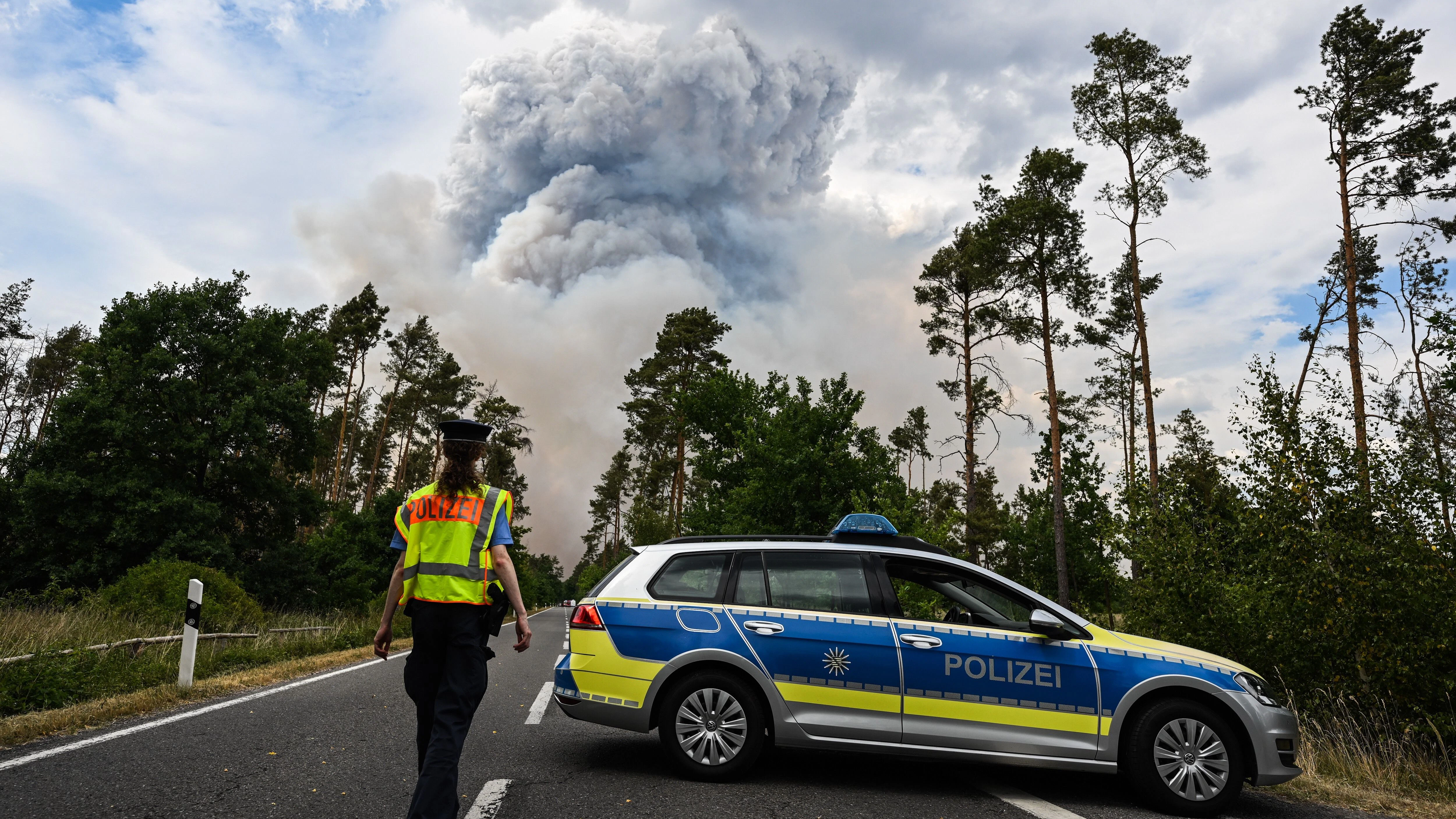 Ein Polizeiauto sperrt die Straße zum Waldbrand-Gebiet ab.