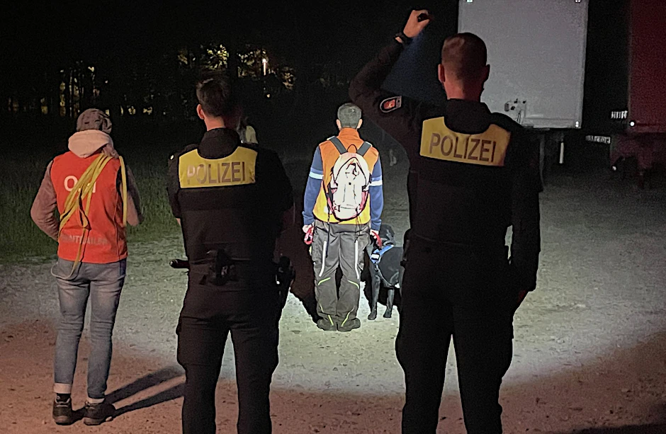 Polizisten und Helfer mit einem Suchhund suchen nach einem vermissten Kind.