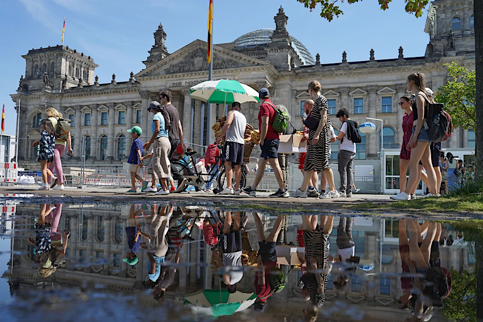 Zahlreiche Menschen gehen bei strahlendem Sonnenschein am Reichstagsgebäude vorbei. Die hohen Temperaturen lösten bei manchem Kreislaufprobleme aus.