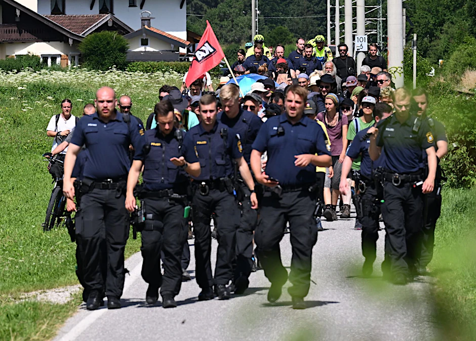 Aktivisten auf einem Sternmarsch zum G7-Gipfel werden von Polizisten begleitet.  