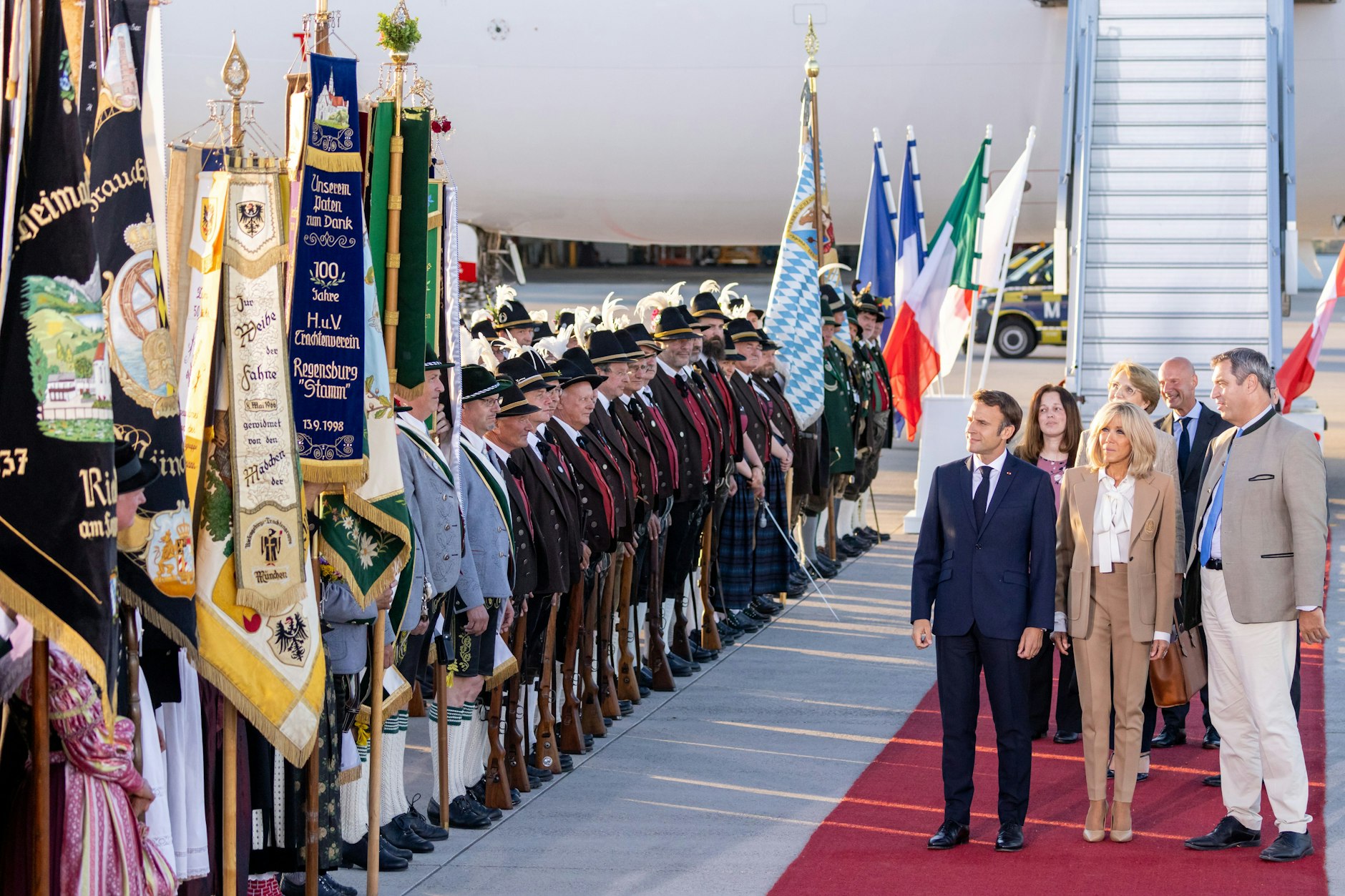 Frankreichs Staatspräsident Emmanuel Macron und Markus Söder gehen an bayerischen Gebirgsschützen und Trachtlern vorbei.