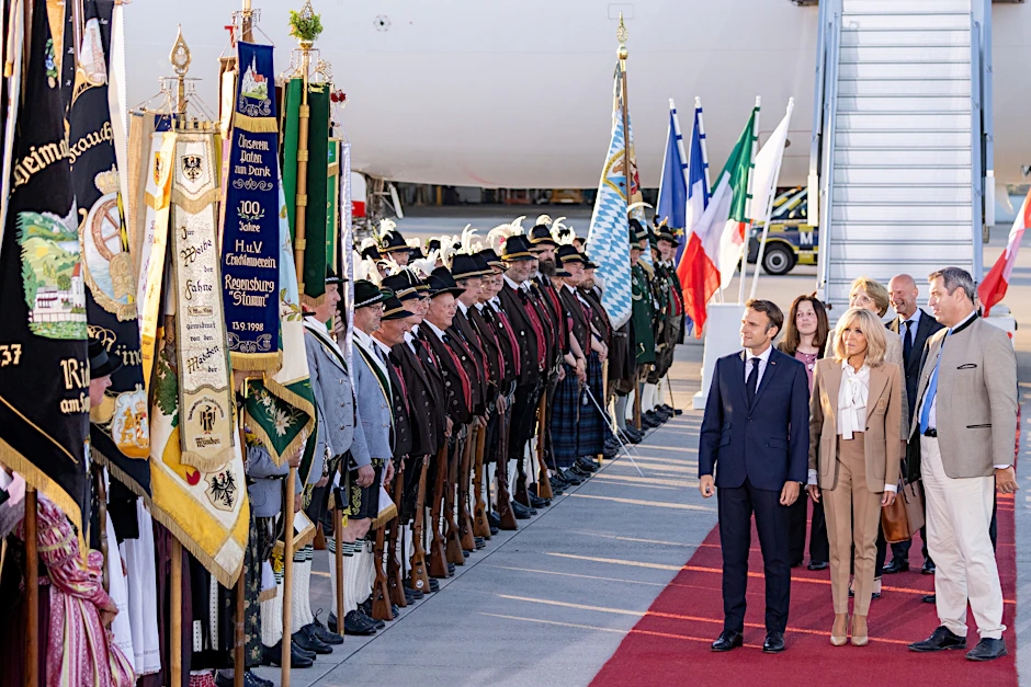 Frankreichs Staatspräsident Emmanuel Macron und Markus Söder gehen an bayerischen Gebirgsschützen und Trachtlern vorbei.