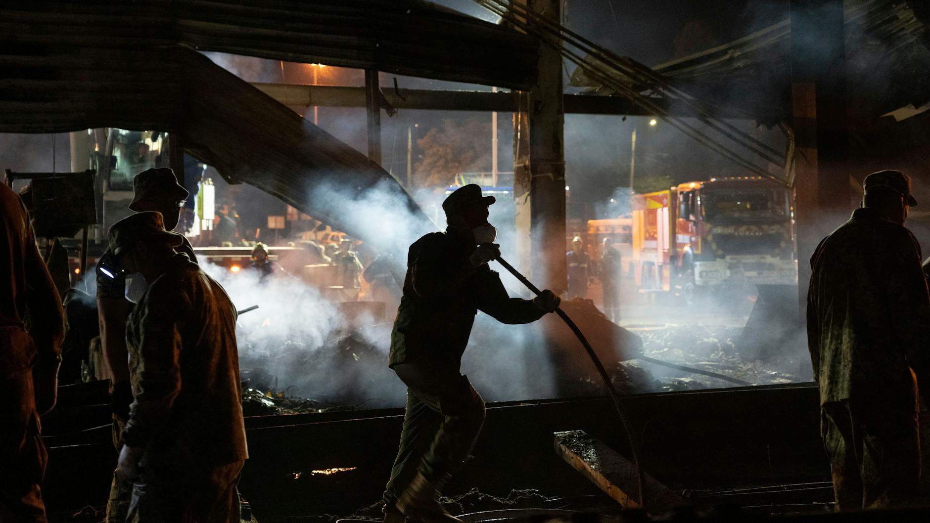 Krementschuk: Freiwillige Helfer und Feuerwehrleute des Staatlichen Katastrophenschutzes beseitigen die Trümmer eines Einkaufszentrums, das nach einem Raketenangriff in Brand geraten ist.