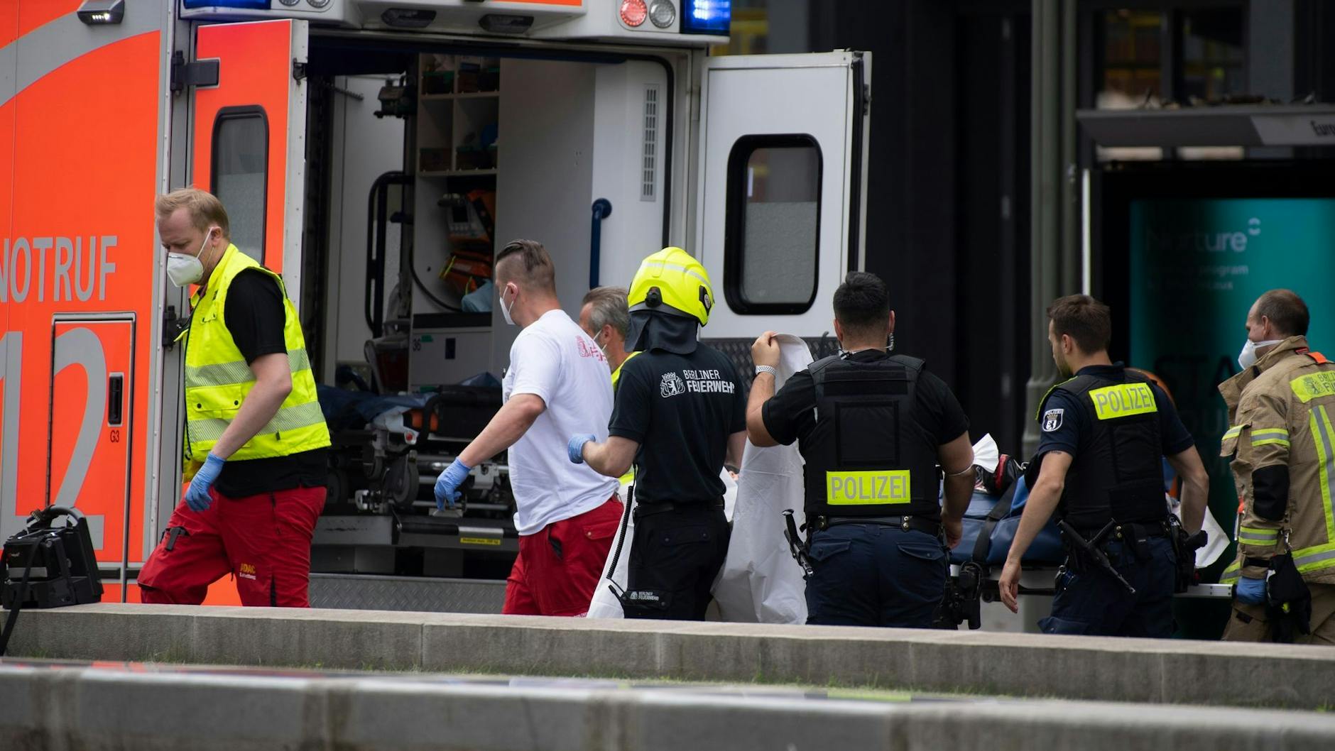 Mitarbeiter von Rettungsdienst, Polizei und Feuerwehr bringen eine Trage in einen Rettungswagen.