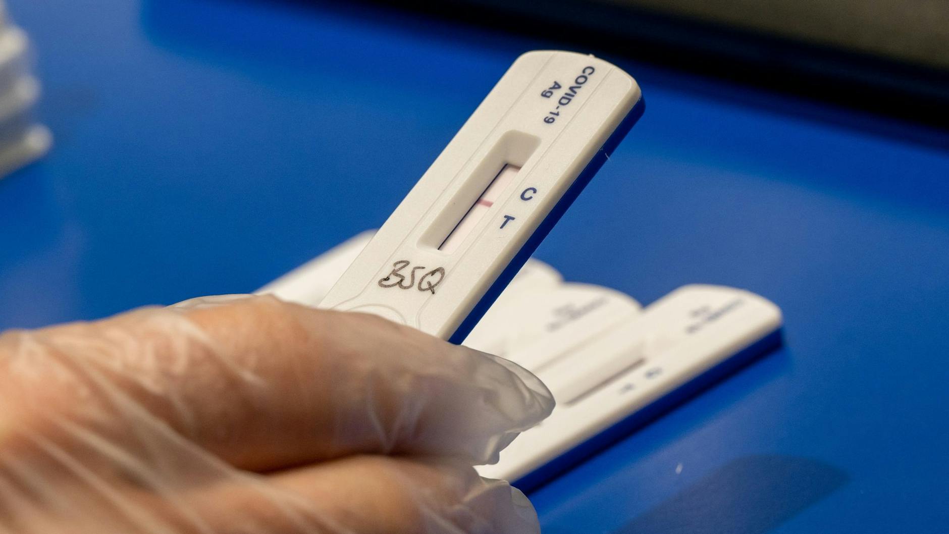 Ein Mitarbeiter einer Apotheke hält einen Corona-Schnelltest in der Hand.