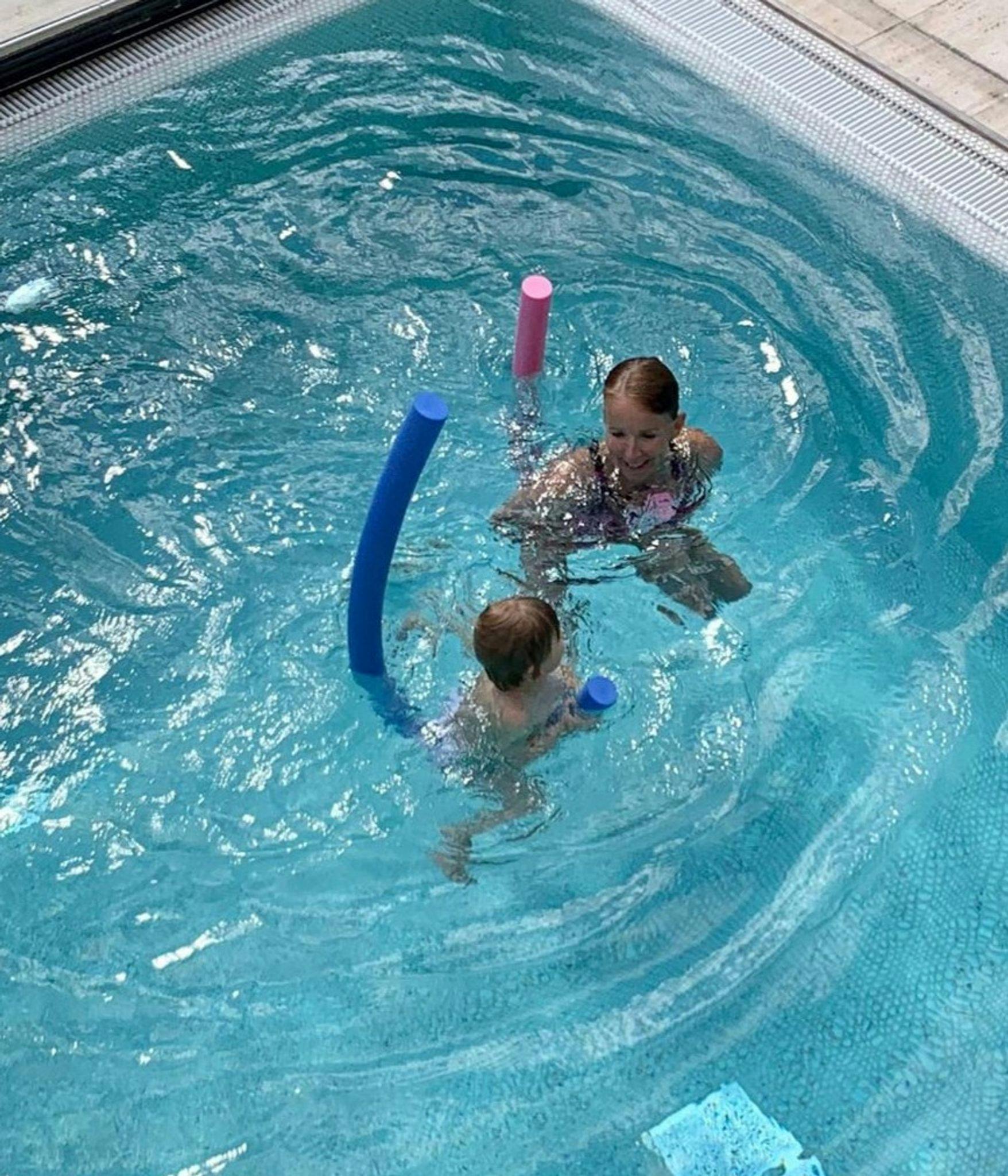 HANDOUT - Eine Trainerin übt mit einem Keinkind in einem Becken Schwimmen. ademy/dpa - ACHTUNG: Nur zur redaktionellen Verwendung im Zusammenhang mit der aktuellen Berichterstattung und nur mit vollständiger Nennung des vorstehenden Credits
