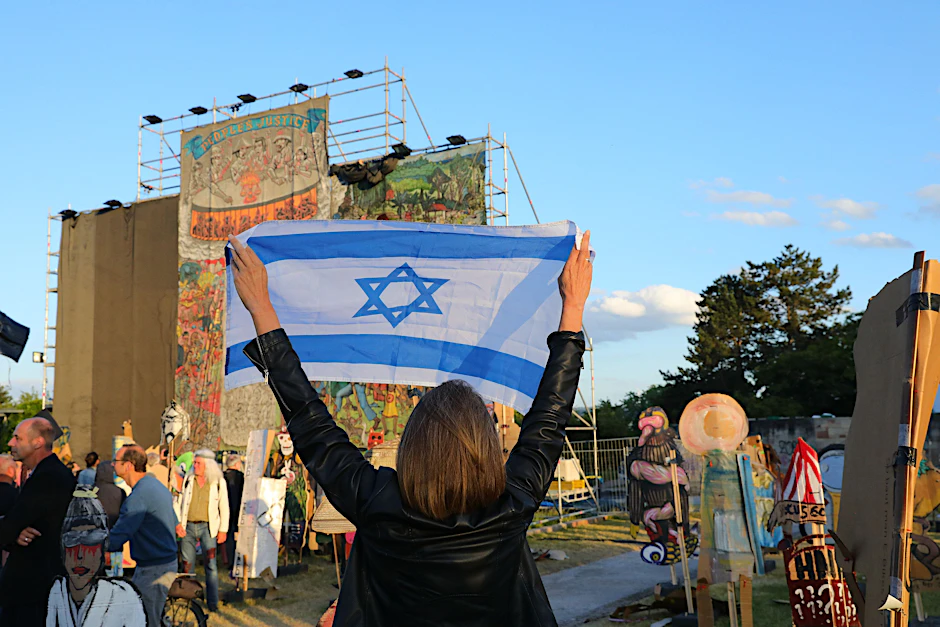 Nach Antisemitismusvorwürfen gegen die Kunstausstellung Documenta fifteen wird eines der gezeigten Werke verhüllt. Davor protestiert eine proisraelische Demonstrantin.