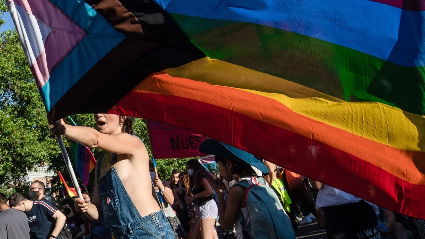 Eine junge Frau schwenkt eine Pride-Fahne. (Symbolbild)