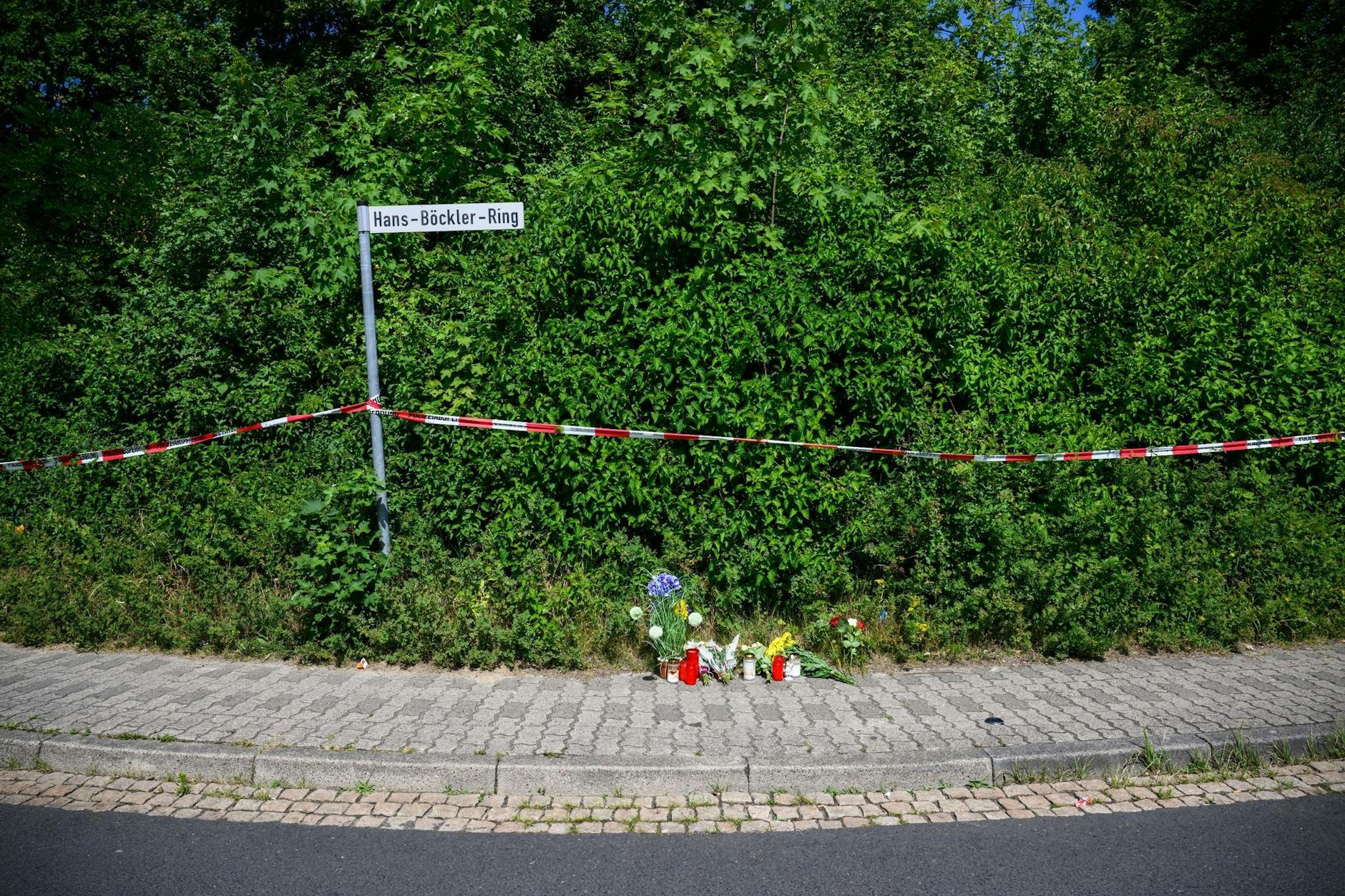 Menschen haben Kerzen, Blumen und Figuren am Tatort abgelegt.