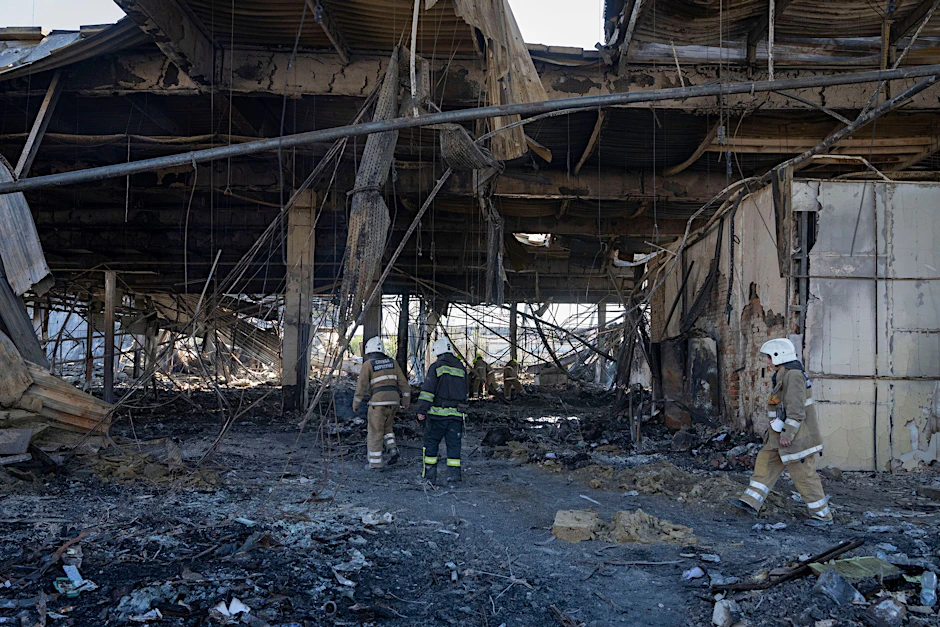 Feuerwehrleute des Staatlichen Katastrophenschutzes beseitigen in Krementschuk die Trümmer des Einkaufszentrums, das nach dem russischen Raketenangriff in Brand geraten ist.  