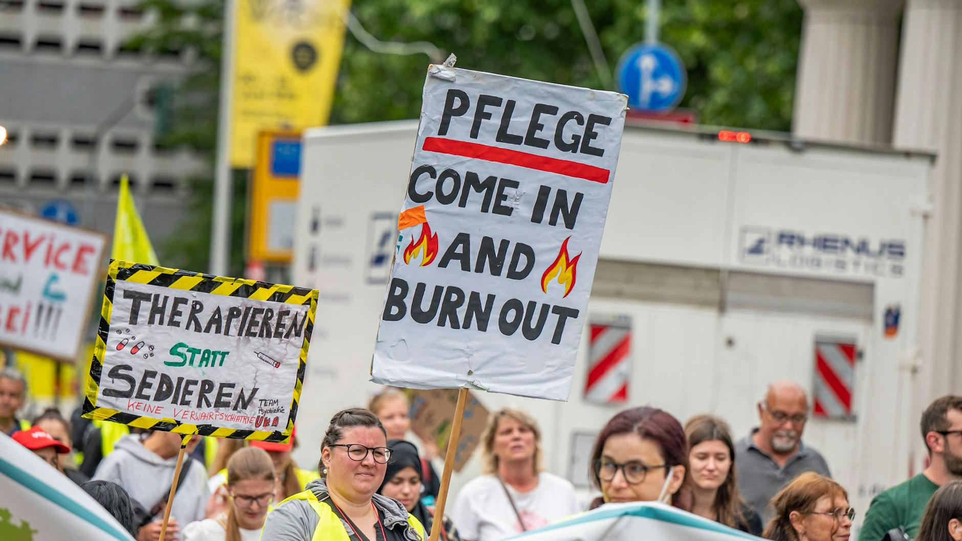 Kundgebung von Pflegepersonal: Menschen tragen Schilder und gelbe Warnwesten.