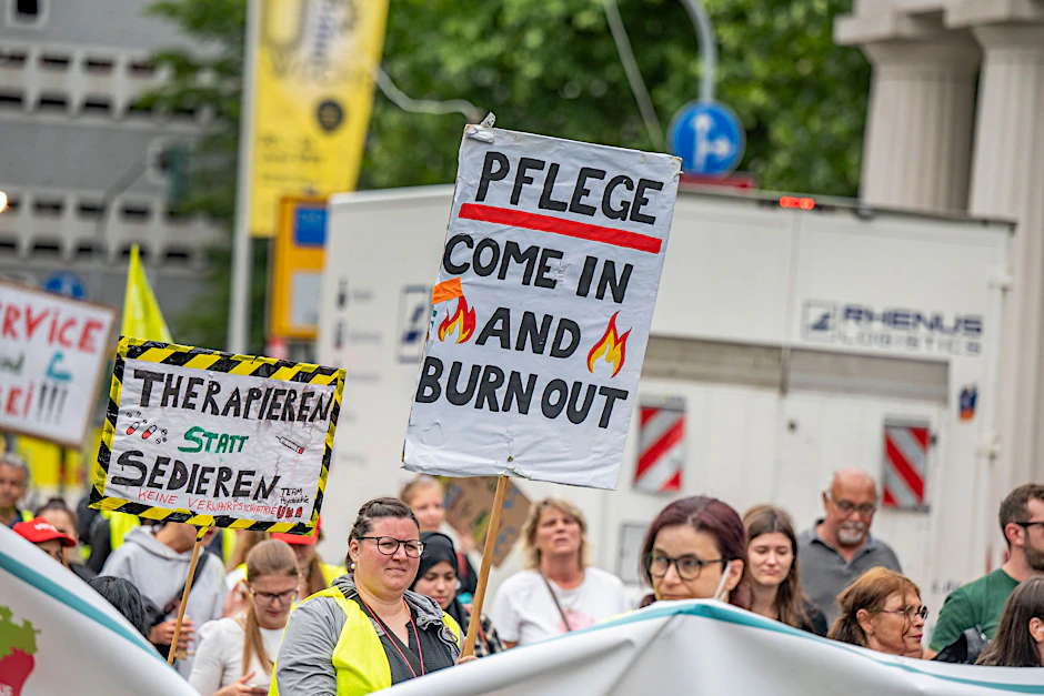 Kundgebung von Pflegepersonal: Menschen tragen Schilder und gelbe Warnwesten.