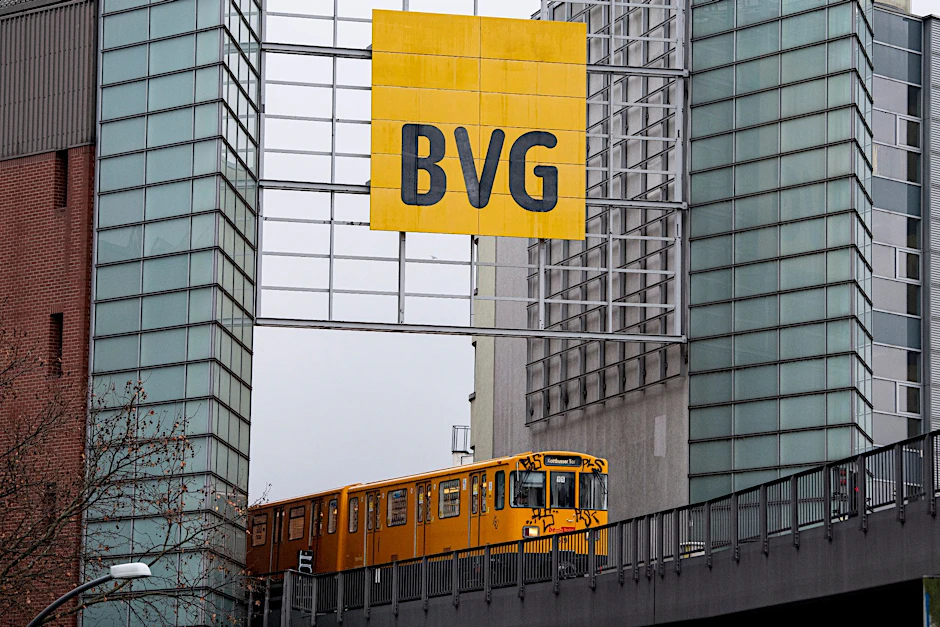 Eine Berliner U-Bahn fährt an einem großem Schild mit dem Logo der BVG vorbei (Symbolbild).