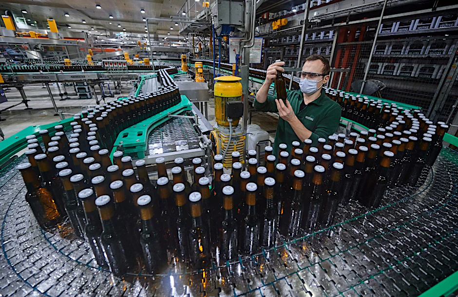 Ein Mitarbeiter kontrolliert in der Flaschenabfüllung der Veltins Brauerei eine Flasche, Januar 2022. Ein Archivfoto.