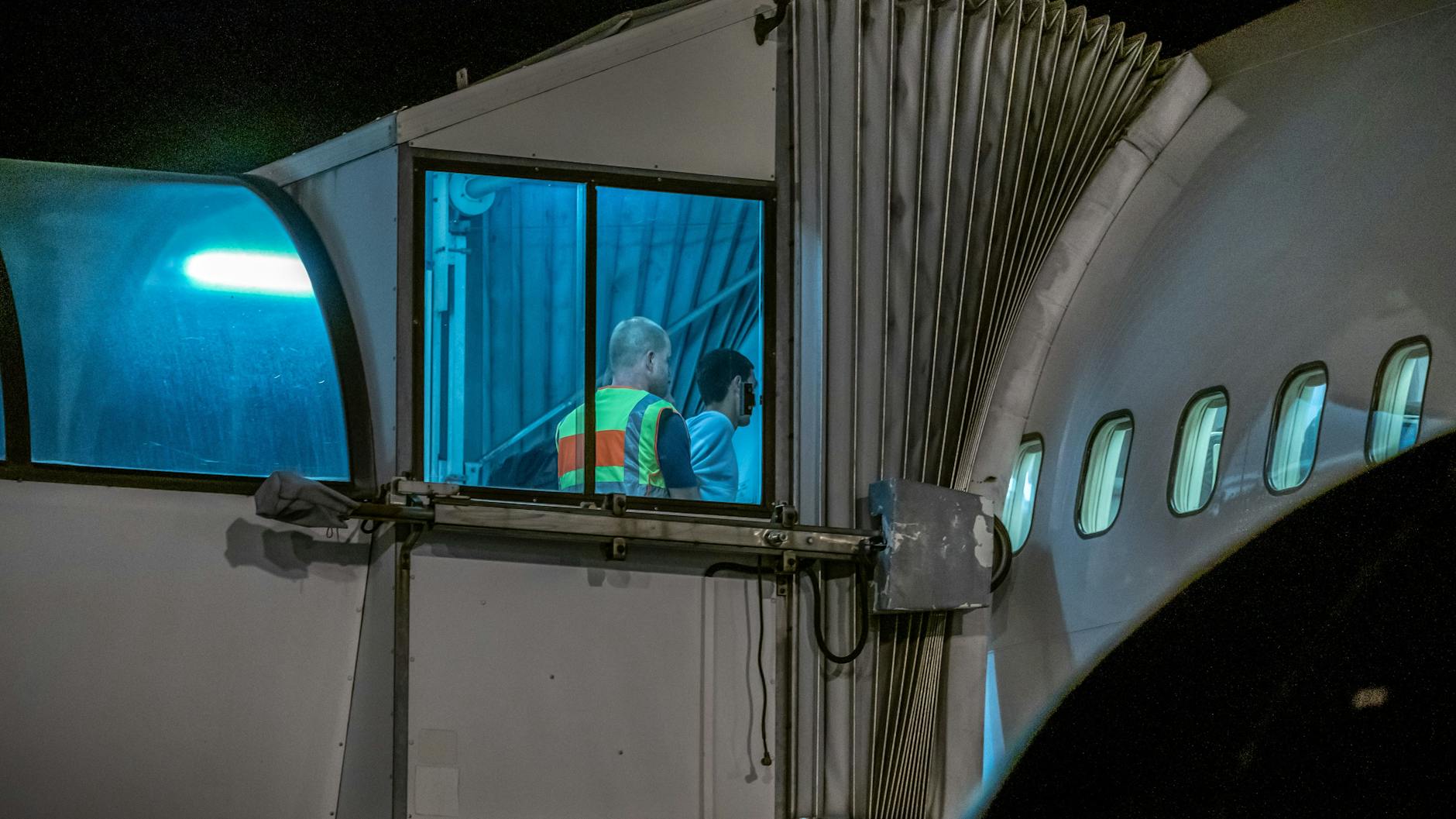 Ein Beamter schiebt eine Person durch den Eingang eines Flugzeuges. (Symbolbild)