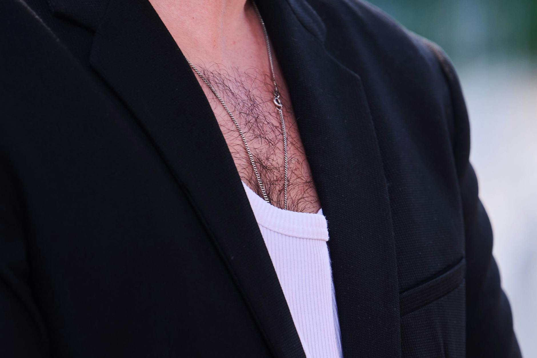 Brusthaar ist bei einem Mann zu sehen, der ein weißes Rippenshirt zu einem Jacket trägt.