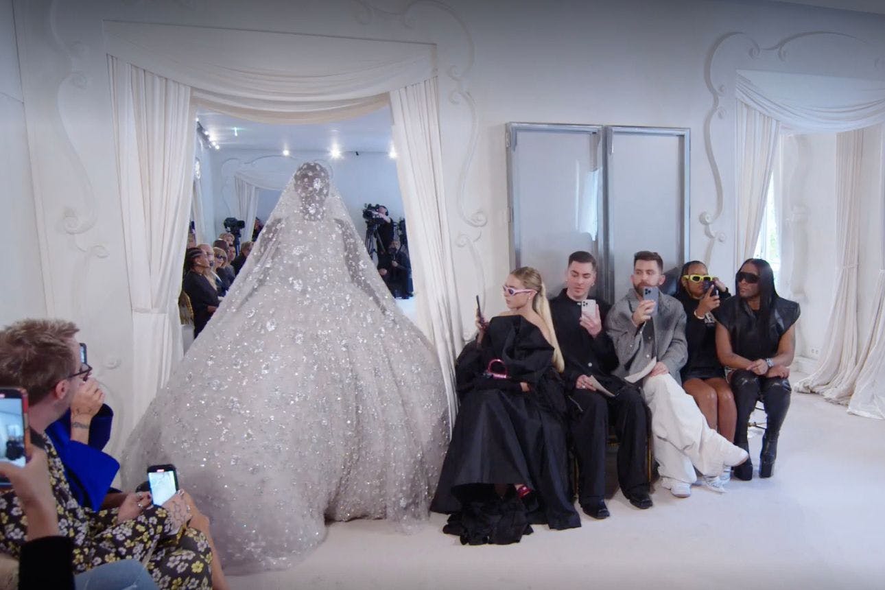 Das kostbarste Kleid der Balenciaga-Show wurde in 7500 Stunden Handarbeit mit Pailletten, Perlen und Kristallen bestickt. Das Model quetscht sich zuerst damit durch die schmale Tür, dann verheddert es sich im Saum.