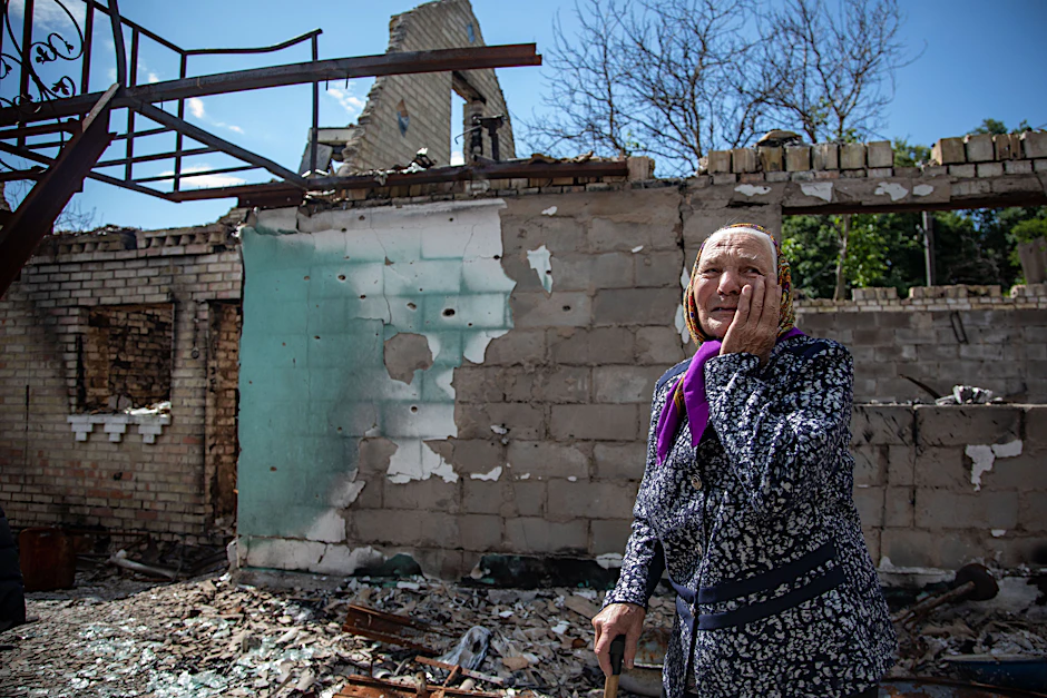 Eine 91-jährige Ukrainerin steht nach einem Beschuss vor ihrem zerstörten Wohnhaus.