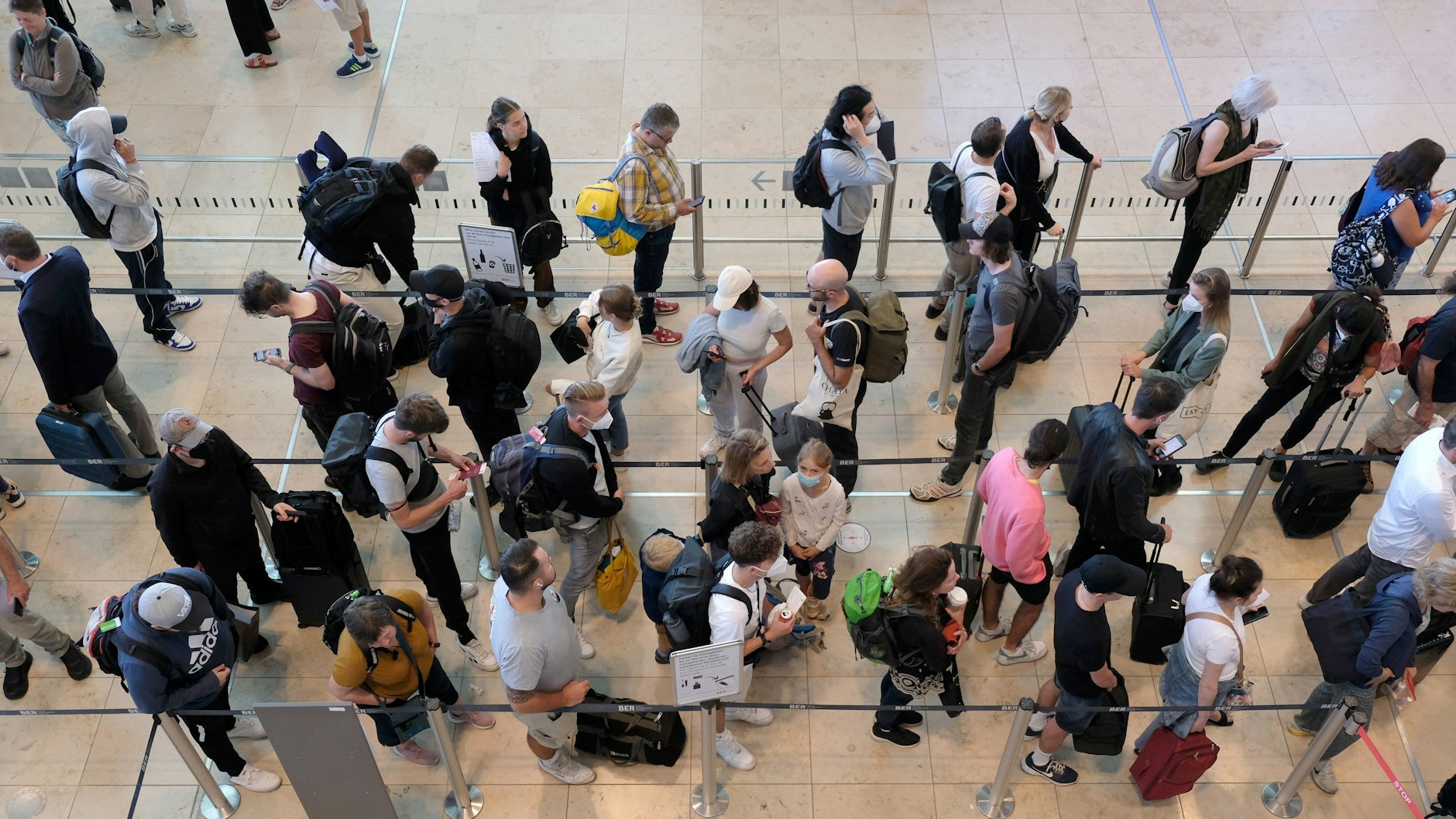 Passagiere stehen in einer Schlange am BER.