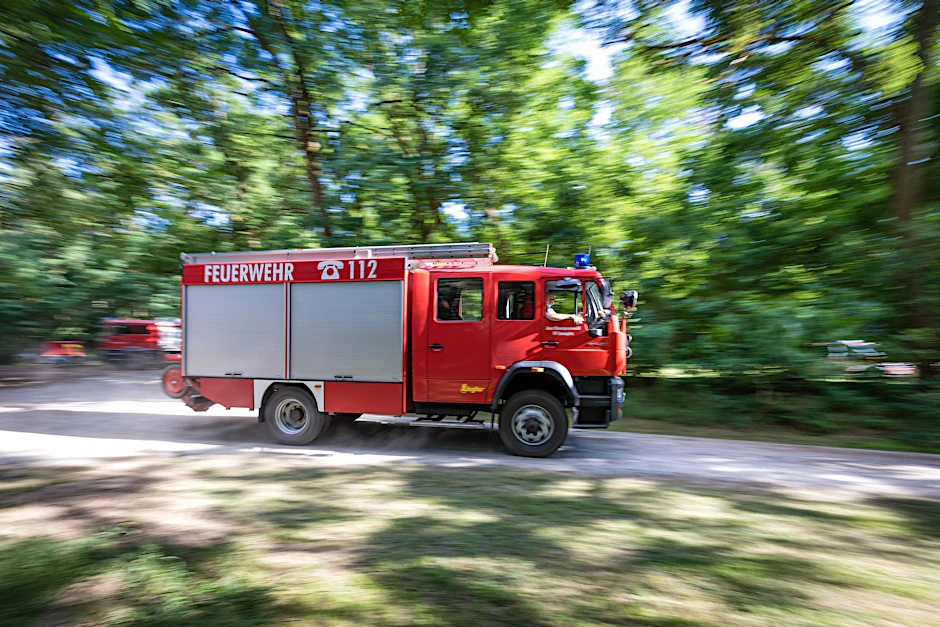 ARCHIV - Ein Fahrzeug der Feuerwehr fährt in der Nähe des Einsatzortes: Die Einsatzkräfte scheinen den Waldbrand in der Lieberoser Heide nun im Griff zu haben.  