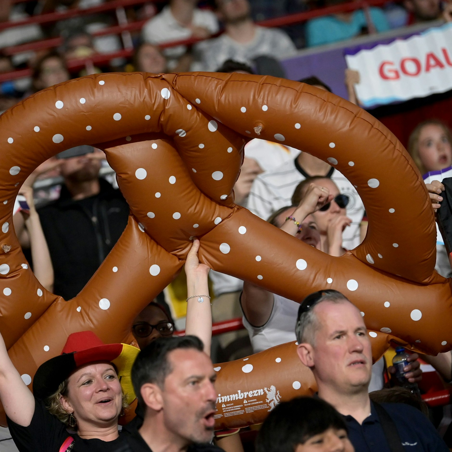Deutsche Fans halten eine vergrößerte Nachbildung einer Brezel in die Höhe und feuern ihre Mannschaft an.