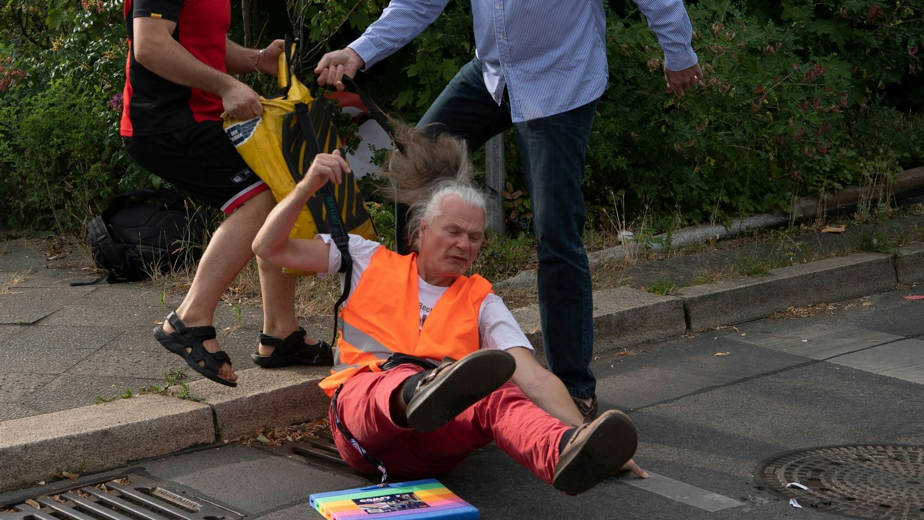 Von wem hier gerade die Gewalt ausgeht, ist unklar: Autofahrer ziehen Aktivisten von der Berliner Straße.