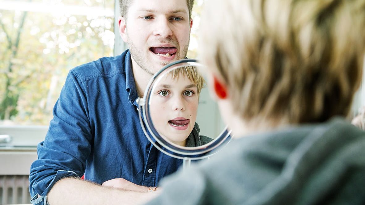 Ein Logopäde arbeitet mit einem kleinen Patienten gegen dessen Muskulatur-Störung im Mundbereich.