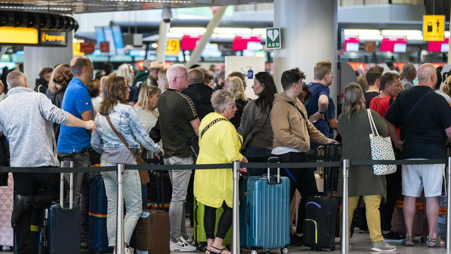 Reisende stehen in der Abflughalle des Amsterdamer Flughafens Schiphol Schlange.