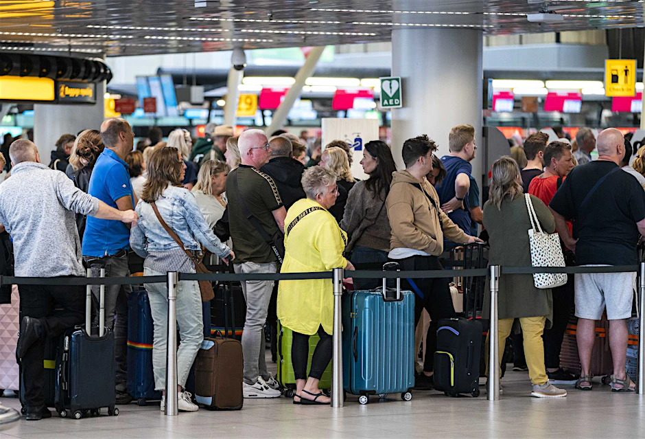 Reisende stehen in der Abflughalle des Amsterdamer Flughafens Schiphol Schlange.