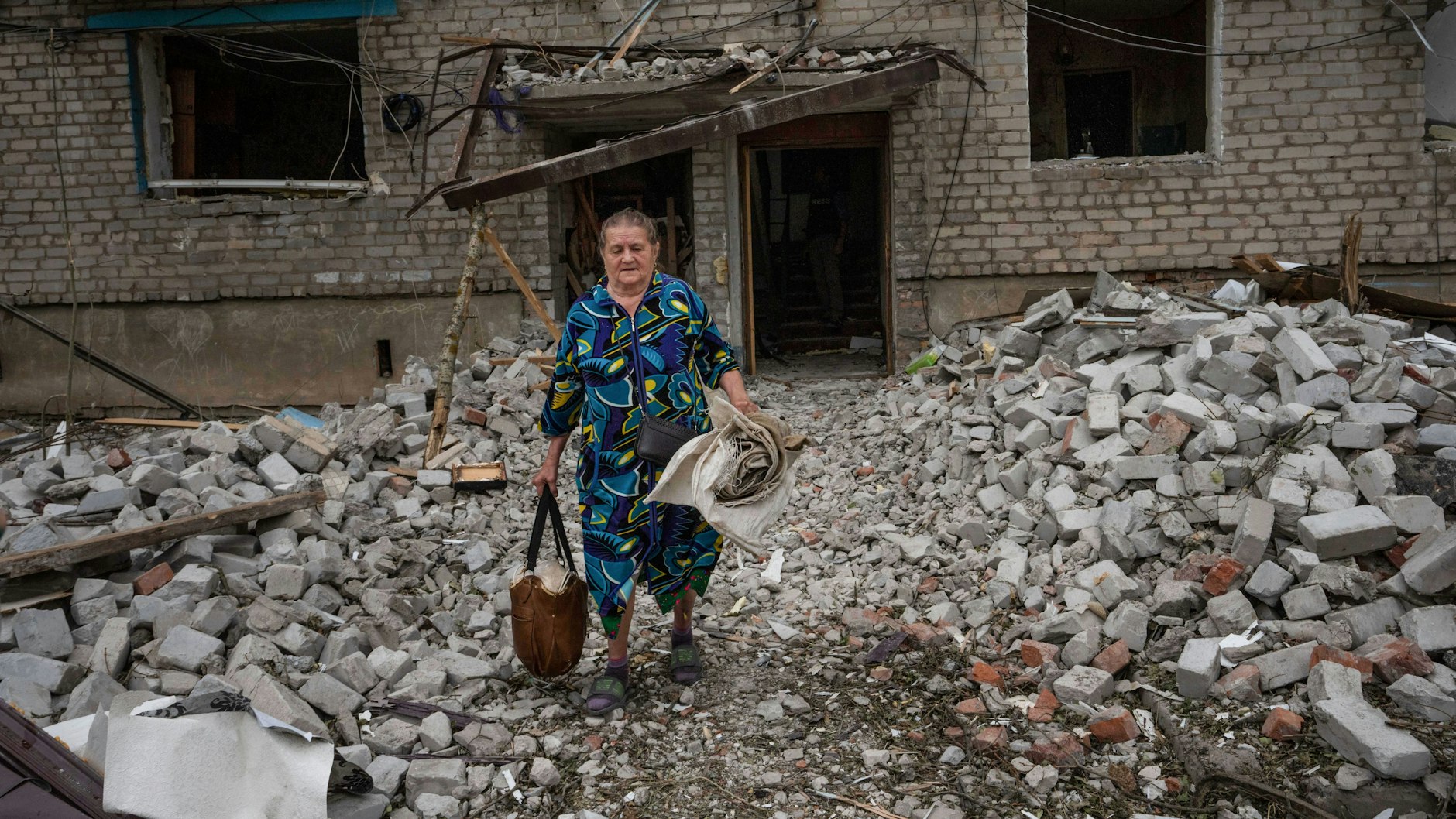 Tschassiw Jar: Eine Frau verlässt ihr zerstörtes Haus mit Habseligkeiten.