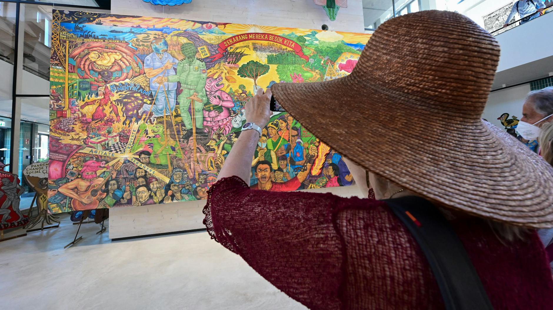 Eine Besucherin vor einem Großbanner des indonesischen Künstlerkollektivs Taring Padi im Hallenbad-Ost in Kassel