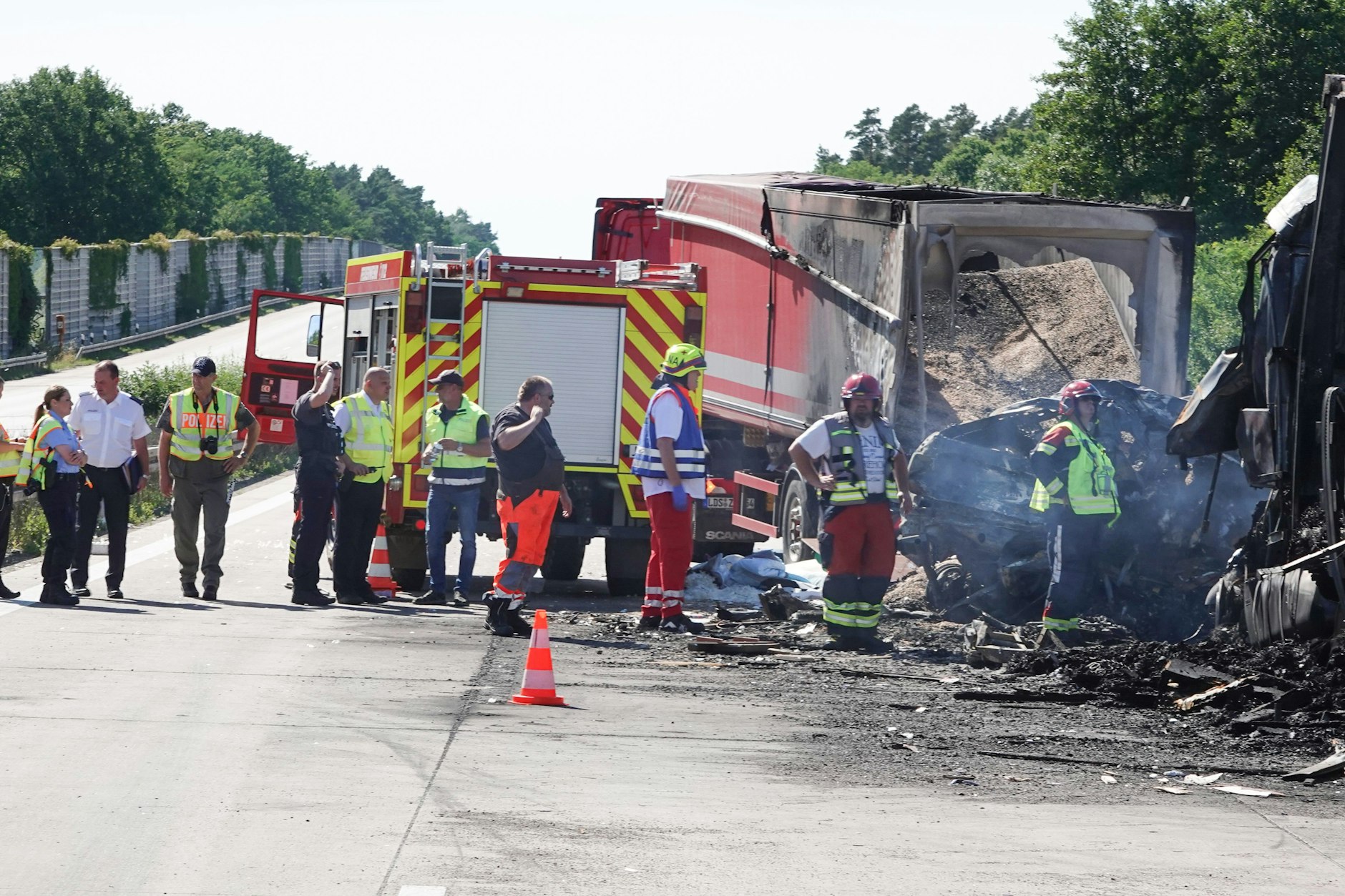 Die Unfallstelle auf der A2 in Sachsen-Anhalt. Rettungskräfte stehen vor ausgebrannten Fahrzeugen.