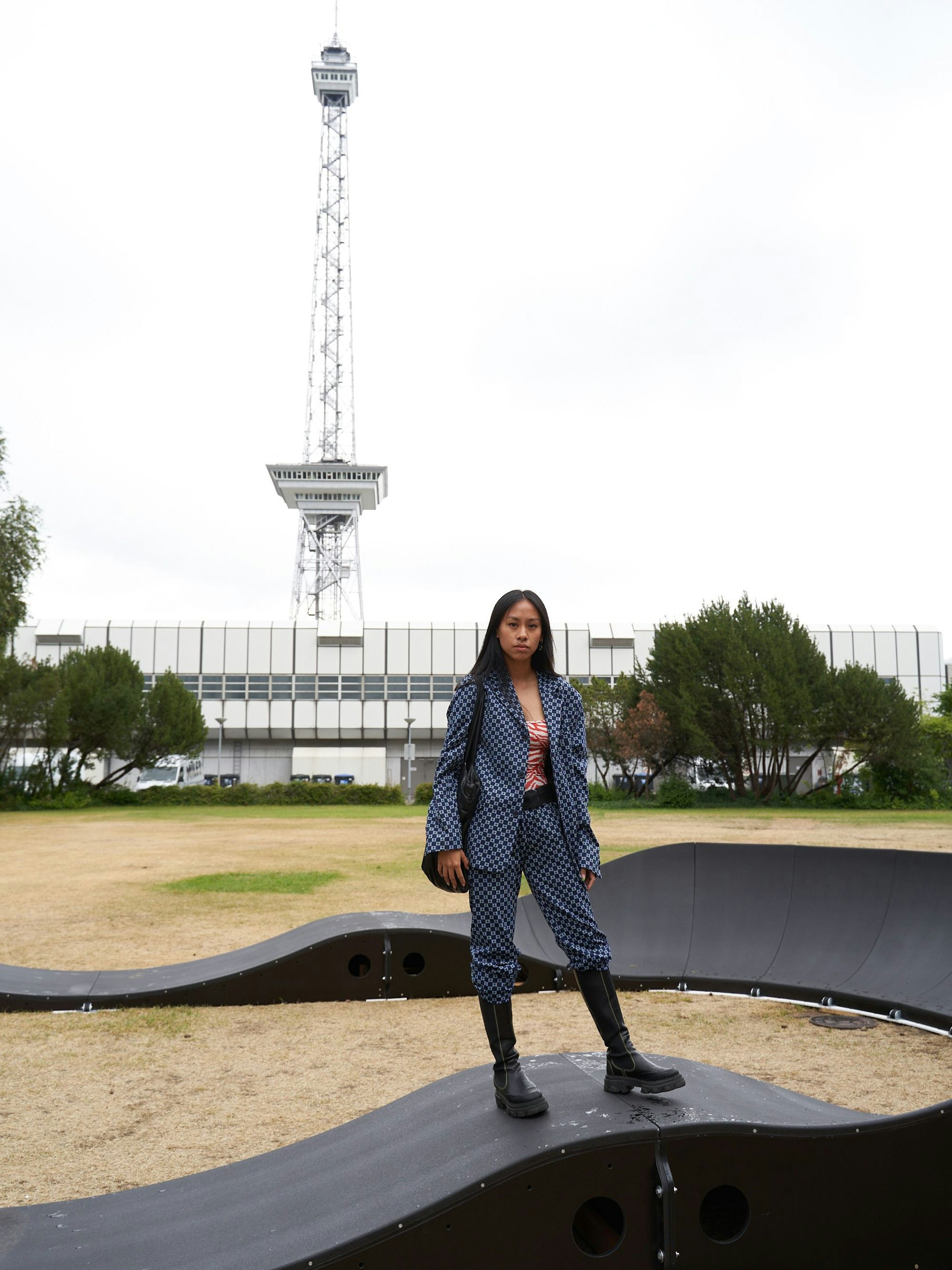 Hue arbeitet im Bereich Mode-PR und beeindruckt mit einem Anzug im All-over-Muster. Die Hosen hat sie in die Stiefel gesteckt, was den Look sowohl regentauglich als auch lässig macht.