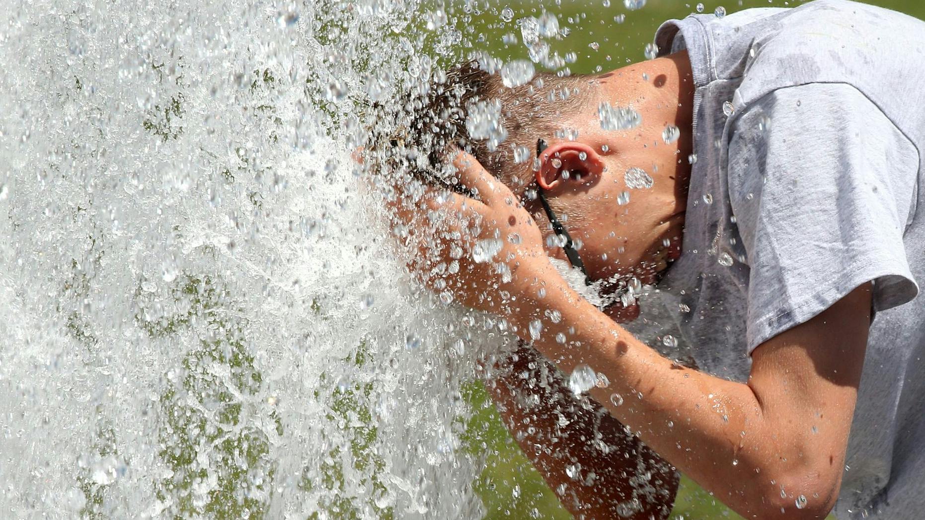 Bei Temperaturen um 29 Grad Celsius erfrischt sich ein junger Mann im Berliner Lustgarten.