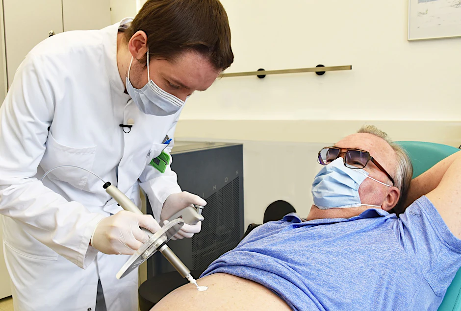 Ein Nuklearmediziner trägt radioaktive Paste beim Patienten auf, die einen Hautkrebs-Tumor abtöten soll.
