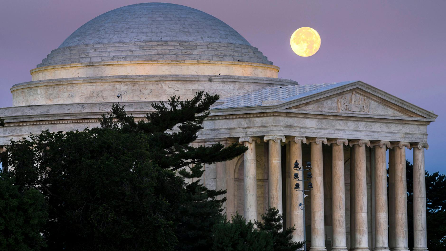 USA, Washington: Der Vollmond geht in der Morgendämmerung hinter dem Jefferson Memorial in Washington unter.