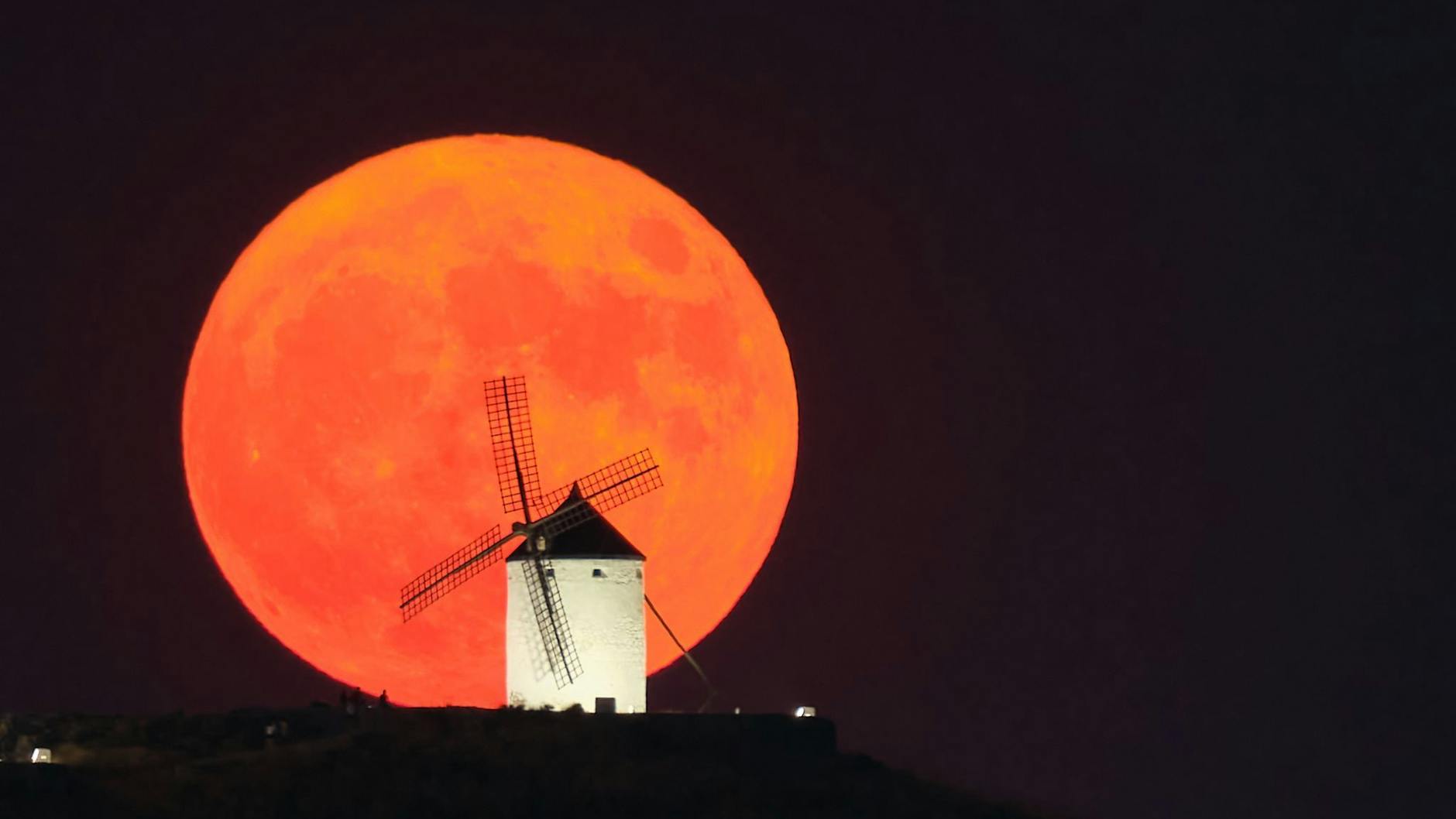 Der Supermond vom Juli 2022 geht hinter einer beleuchteten Windmühle spanischen Consuegra auf.