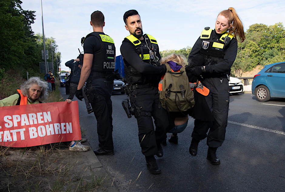 Polizeibeamte tragen Demonstranten von der Stadtautobahn im Berliner Stadtteil Schöneberg. Diese wurde noch am Freitag von Aktivisten der Letzten Generation blockiert.