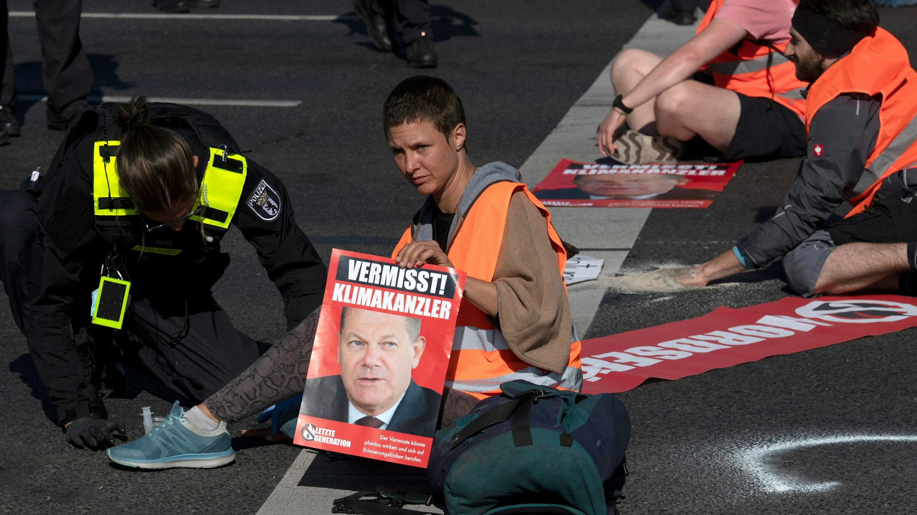 Eine Person demonstriert mit Sitzblockade auf einer Autobahn für den Klimaschutz.