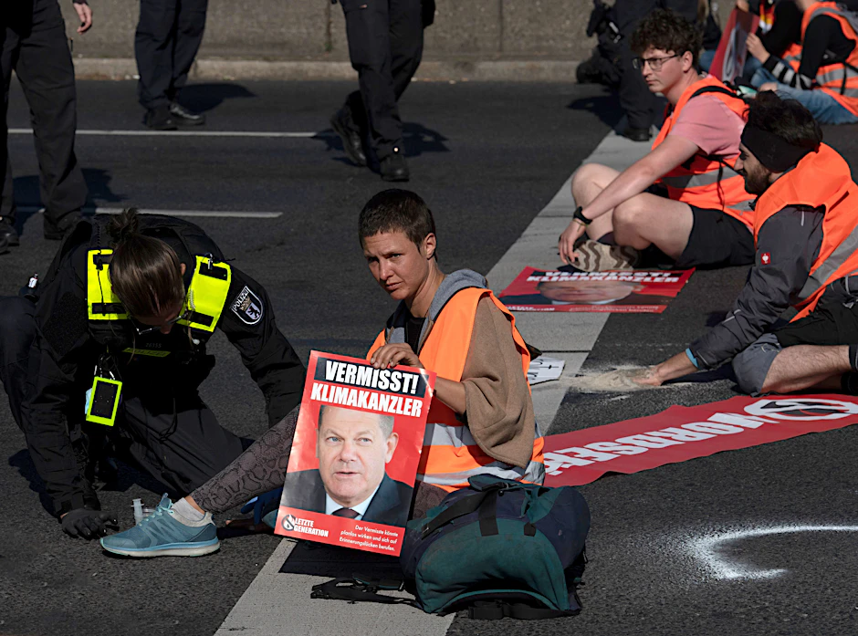 Eine Person demonstriert mit Sitzblockade auf einer Autobahn für den Klimaschutz.