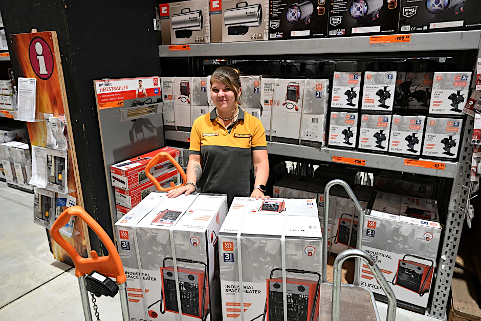 Eine Mitarbeiterin bei Hornbach räumt einen Heizlüfter aus einem Regal auf einen Wagen.