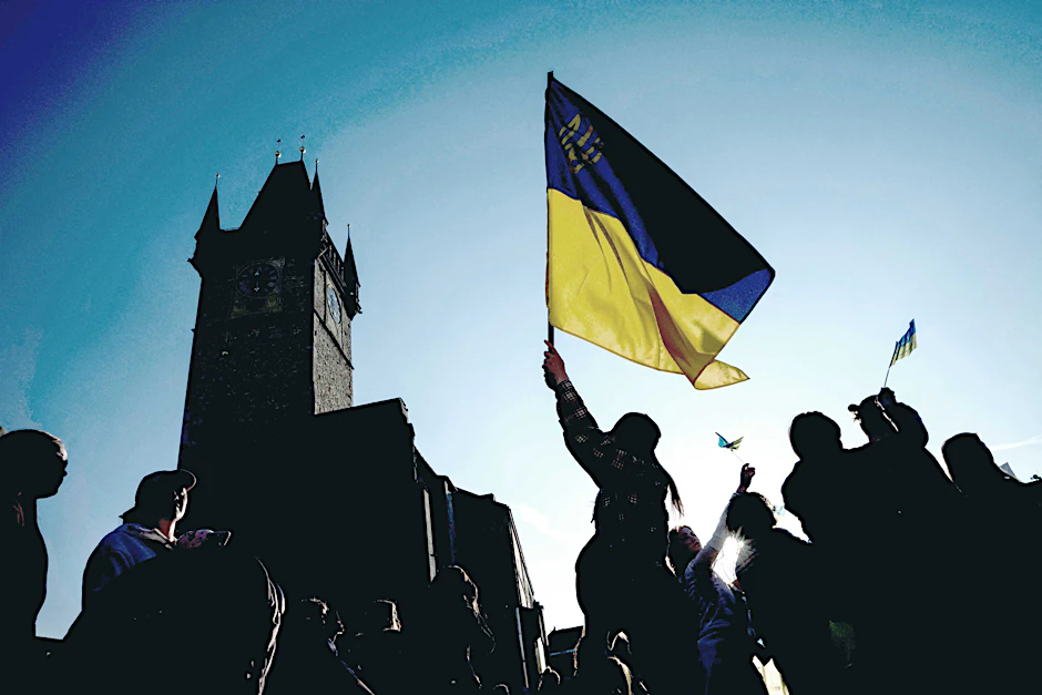 Menschen in Prag zeigen eine ukrainische Flagge, während sie die Übertragung des internationalen Charity-Konzerts „Rettet die Ukraine - Stoppt den Krieg“ aus Warschau am 27. März 2022 verfolgen