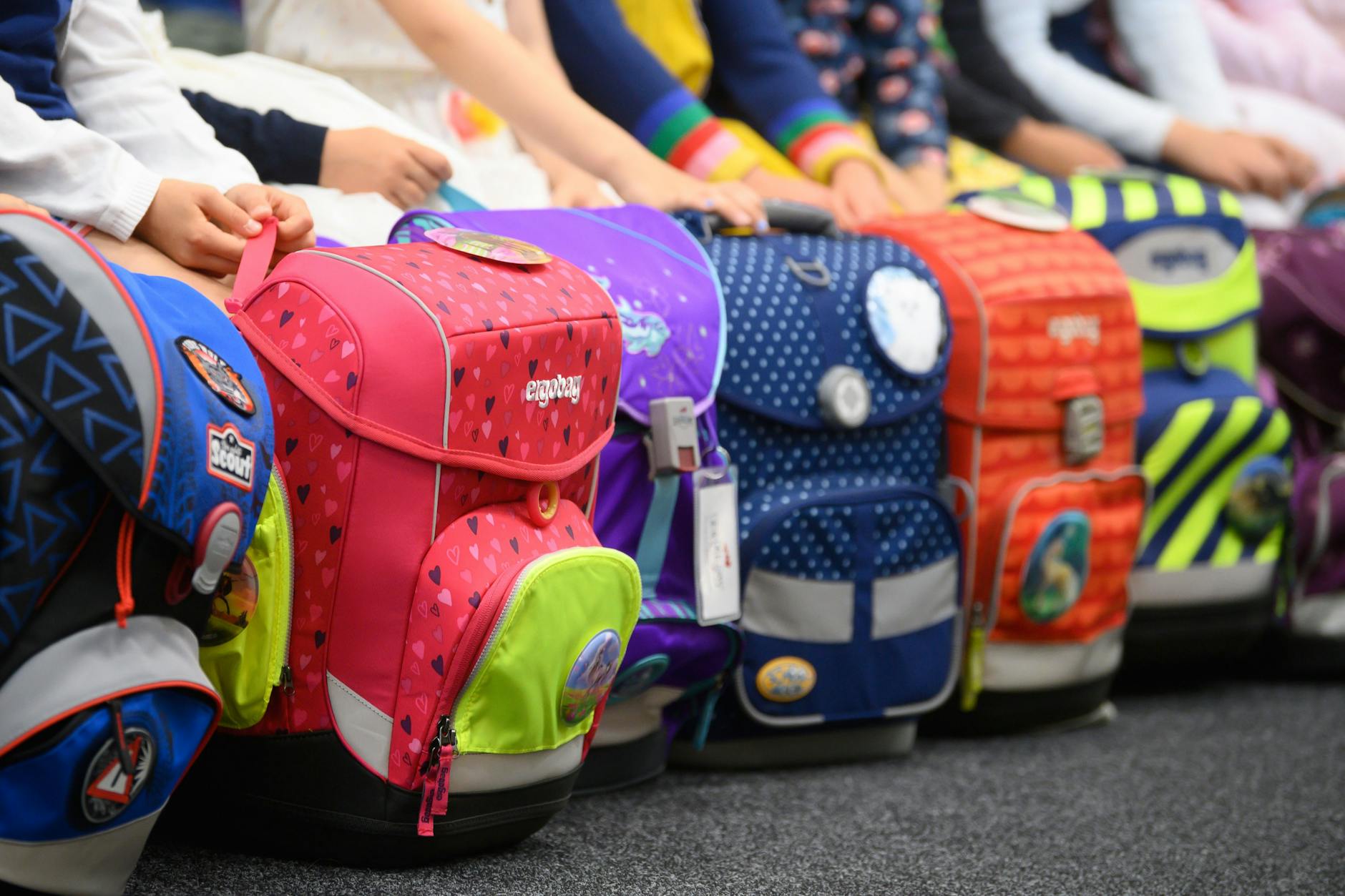 Schulanfänger haben während einer Schuleingangsfeier ihre Schulranzen vor sich abgestellt. (Symbolbild)