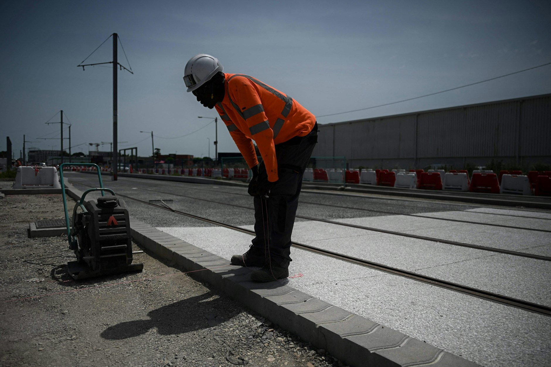 Ein Arbeiter stöhnt im Straßenbau auf einer Baustelle bei 42 Grad Hitze.